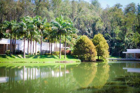 Imagem mostra o museu natural de Inhotim, ela tem um lago rodeado de árvores.